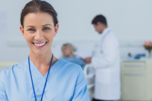 Cheerful surgeon posing with doctor attending patient on background